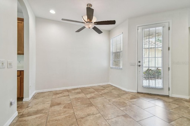spare room featuring a ceiling fan, arched walkways, baseboards, recessed lighting, and light tile patterned flooring