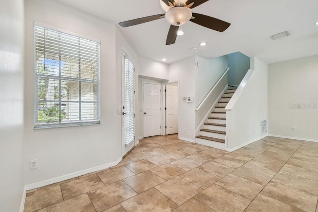 foyer featuring visible vents, stairs, ceiling fan, and a healthy amount of sunlight