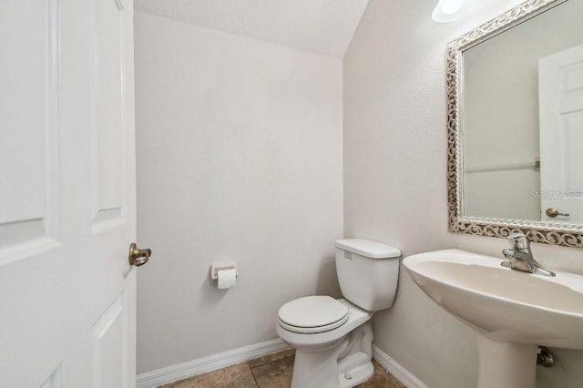 bathroom featuring toilet, baseboards, a sink, and tile patterned floors