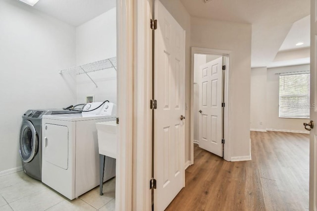 laundry room with baseboards, laundry area, light wood-type flooring, and washing machine and clothes dryer