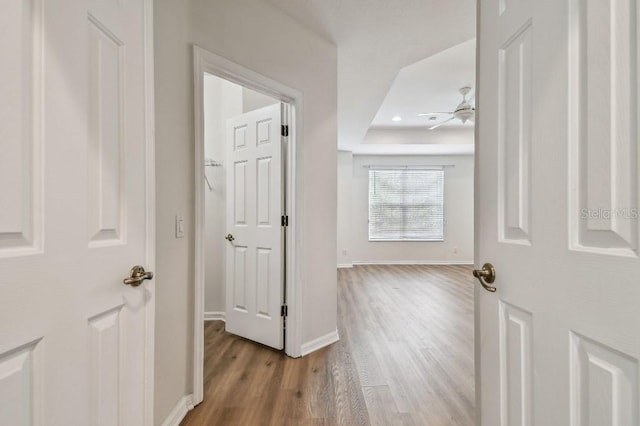 hall with a raised ceiling, baseboards, recessed lighting, and wood finished floors