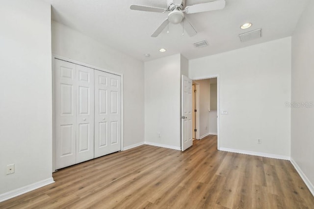 unfurnished bedroom featuring baseboards, wood finished floors, and a closet