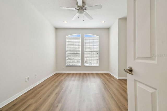 spare room featuring baseboards, ceiling fan, and light wood-style floors