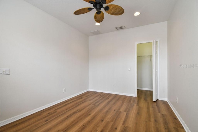 unfurnished bedroom featuring a walk in closet, baseboards, a closet, and wood finished floors