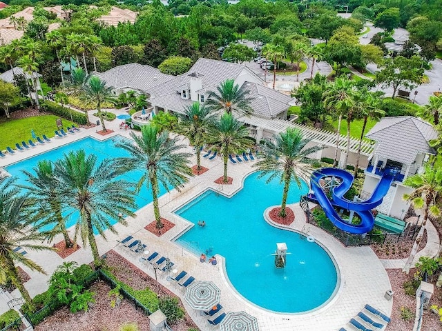 pool with a patio, a water slide, and fence