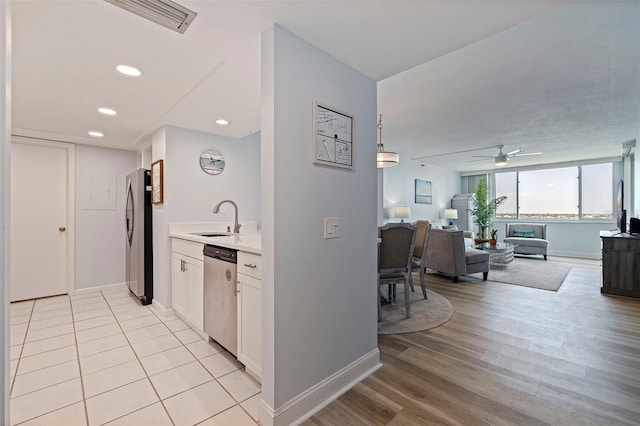 kitchen featuring white cabinets, a sink, light countertops, stainless steel appliances, and baseboards