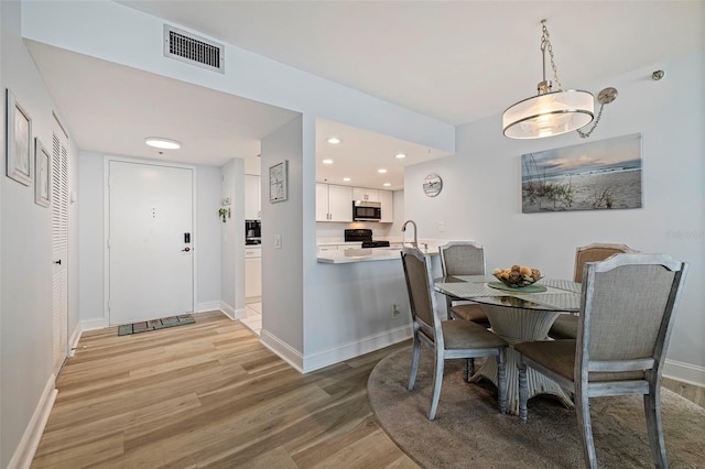 dining space with recessed lighting, baseboards, light wood-type flooring, and visible vents