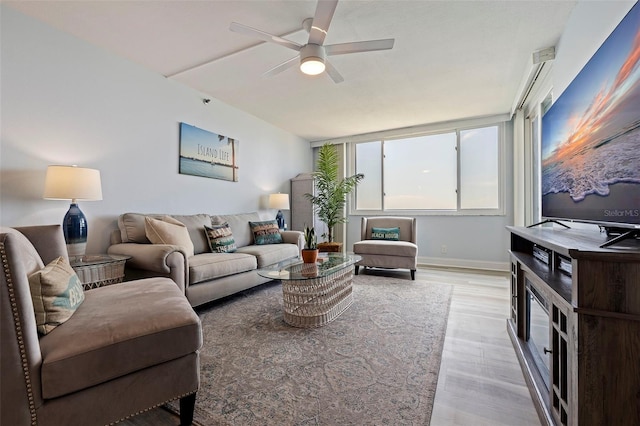 living room featuring ceiling fan, baseboards, and light wood-type flooring