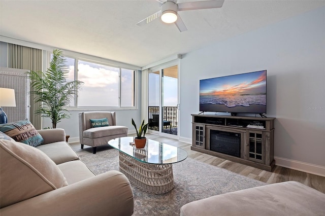 living area with baseboards, a ceiling fan, and wood finished floors
