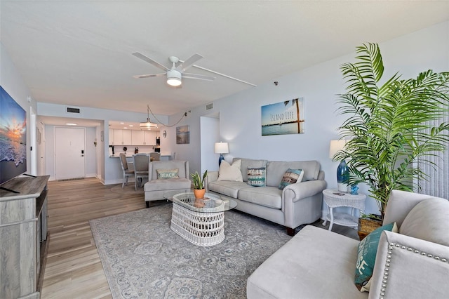 living room with a ceiling fan, visible vents, and light wood-style flooring