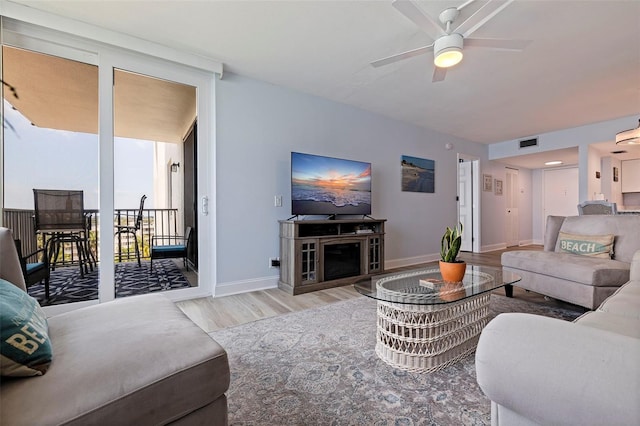 living room with a ceiling fan, baseboards, visible vents, and wood finished floors