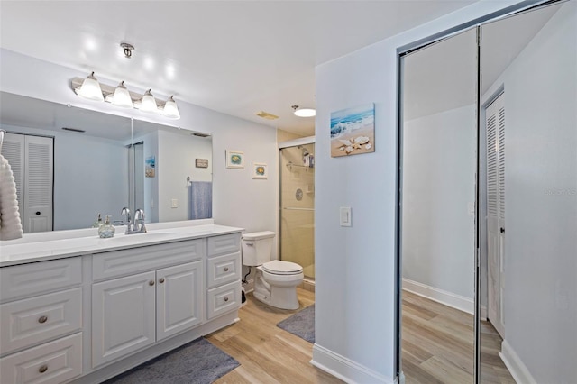full bath with a shower stall, wood finished floors, vanity, a closet, and toilet