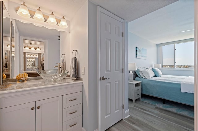 bathroom featuring vanity, baseboards, ensuite bath, and wood finished floors