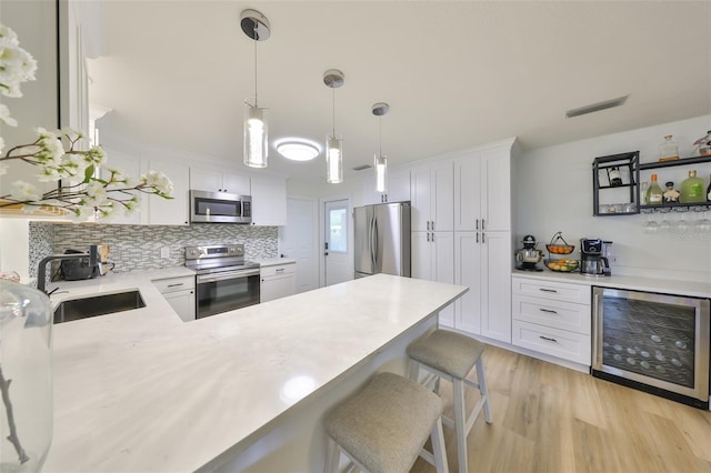 kitchen featuring a sink, light countertops, beverage cooler, stainless steel appliances, and white cabinetry