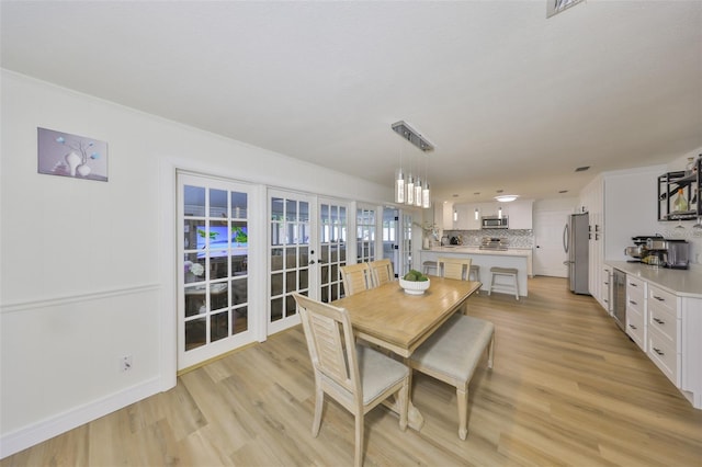 dining space with french doors and light wood-style flooring