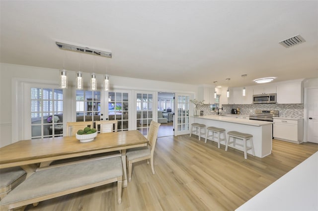 dining space featuring a healthy amount of sunlight, french doors, light wood-style flooring, and visible vents