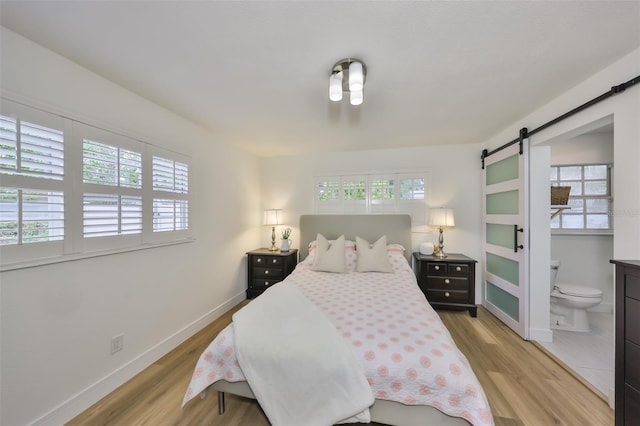 bedroom featuring multiple windows, a barn door, and wood finished floors