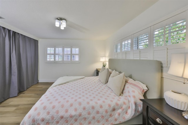 bedroom with baseboards, multiple windows, and light wood-style flooring