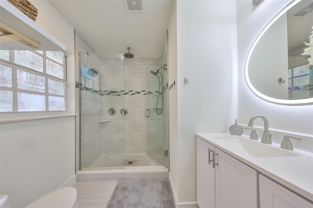 bathroom featuring visible vents, vanity, toilet, baseboards, and a stall shower