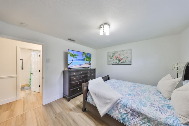 bedroom with baseboards, visible vents, and light wood-style floors
