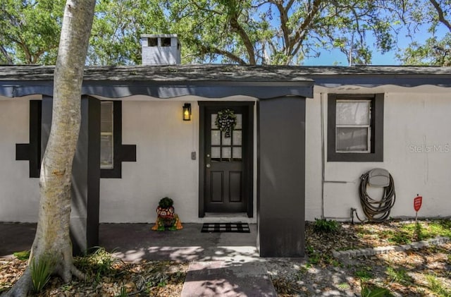 1247 21st St, Sarasota, FL 34234 - doorway to property featuring stucco siding and a chimney