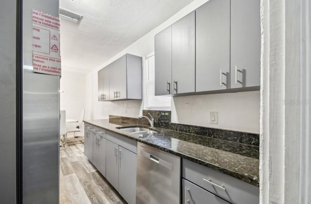 1247 21st St, Sarasota, FL 34234 - kitchen with stainless steel dishwasher, a sink, gray cabinets, light wood-style floors, and a textured ceiling