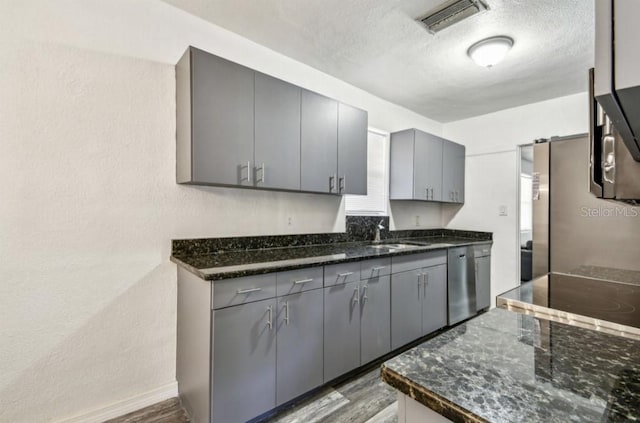 1247 21st St, Sarasota, FL 34234 - kitchen with dishwasher, a sink, gray cabinetry, wood finished floors, and a textured ceiling