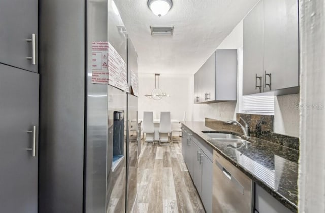 1247 21st St, Sarasota, FL 34234 - kitchen with a sink, appliances with stainless steel finishes, gray cabinetry, dark stone countertops, and light wood-style flooring