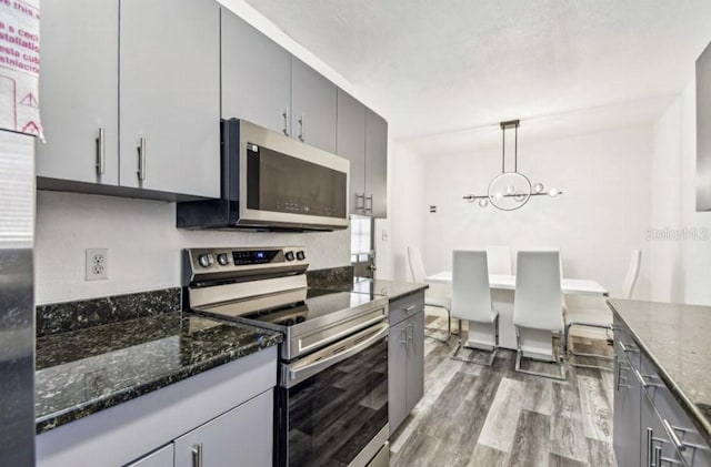 1247 21st St, Sarasota, FL 34234 - kitchen featuring stainless steel appliances, wood finished floors, gray cabinets, and a chandelier