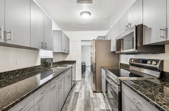 1247 21st St, Sarasota, FL 34234 - kitchen featuring appliances with stainless steel finishes, gray cabinetry, light wood-type flooring, a sink, and a textured ceiling