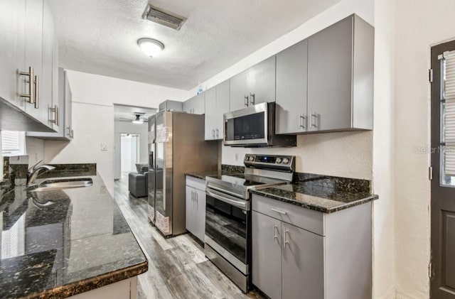 1247 21st St, Sarasota, FL 34234 - kitchen with stainless steel appliances, a sink, gray cabinets, light wood-style flooring, and a textured ceiling