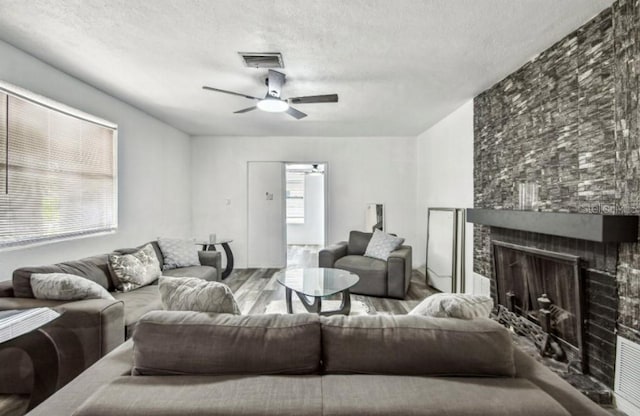 1247 21st St, Sarasota, FL 34234 - living area featuring wood finished floors, a ceiling fan, a textured ceiling, and a fireplace