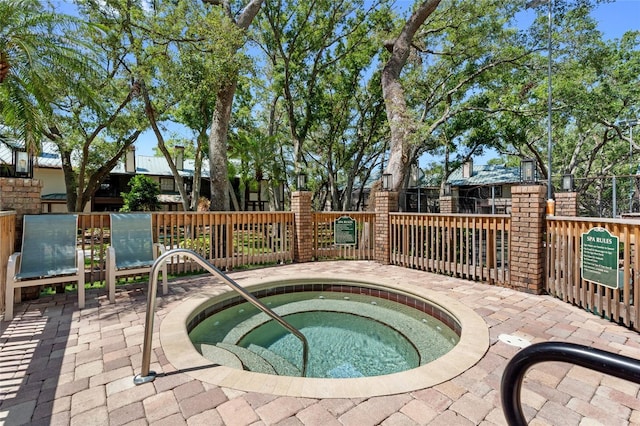 view of swimming pool featuring a hot tub and fence