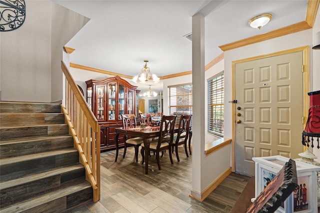 foyer featuring a notable chandelier, stairs, baseboards, wood finished floors, and ornamental molding