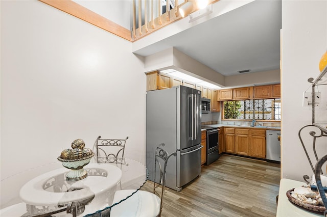 kitchen featuring visible vents, appliances with stainless steel finishes, light wood-type flooring, a sink, and light countertops