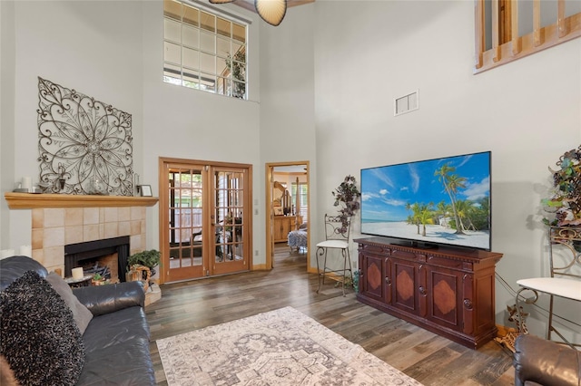 living area with a high ceiling, a fireplace, wood finished floors, and visible vents
