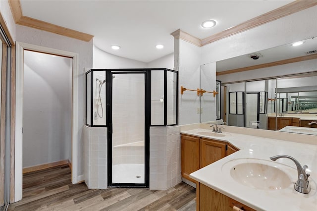 full bath with ornamental molding, a shower stall, a sink, and wood finished floors