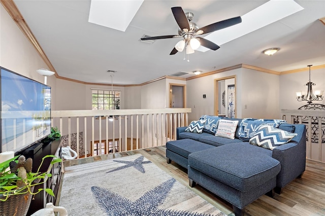 living area with visible vents, crown molding, a skylight, wood finished floors, and ceiling fan with notable chandelier