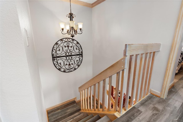 staircase featuring crown molding, baseboards, wood finished floors, and a chandelier