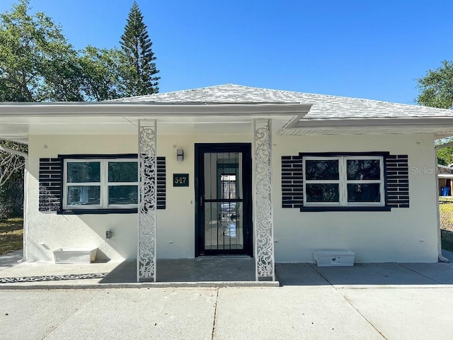 547 16th Ave S, Saint Petersburg, FL 33701 - view of exterior entry with stucco siding and a shingled roof