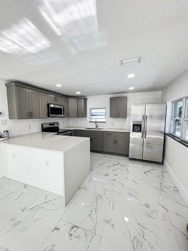 547 16th Ave S, Saint Petersburg, FL 33701 - kitchen with appliances with stainless steel finishes, a sink, light marble finish floors, a peninsula, and baseboards