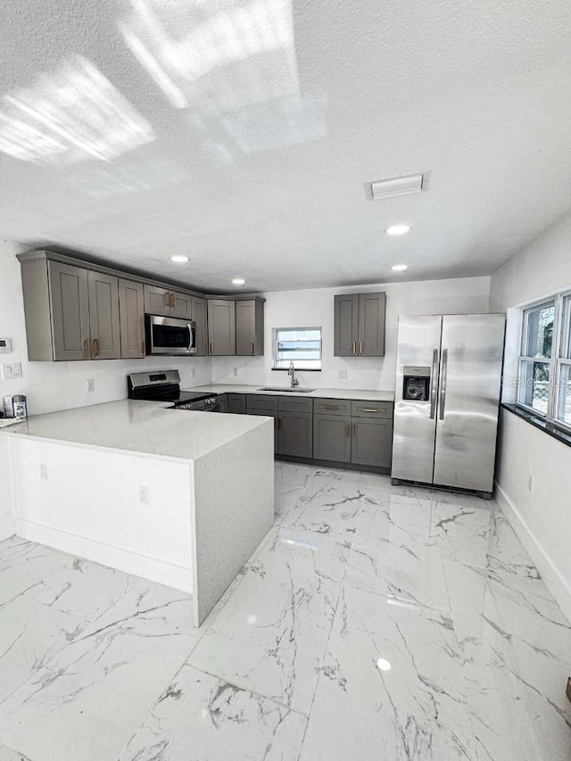 547 16th Ave S, Saint Petersburg, FL 33701 - kitchen featuring stainless steel appliances, a sink, light marble finish floors, a peninsula, and light countertops