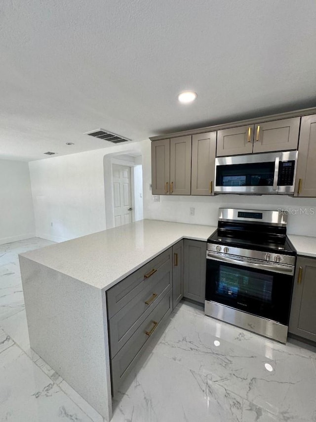 547 16th Ave S, Saint Petersburg, FL 33701 - kitchen featuring appliances with stainless steel finishes, light marble finish flooring, gray cabinetry, light countertops, and a peninsula