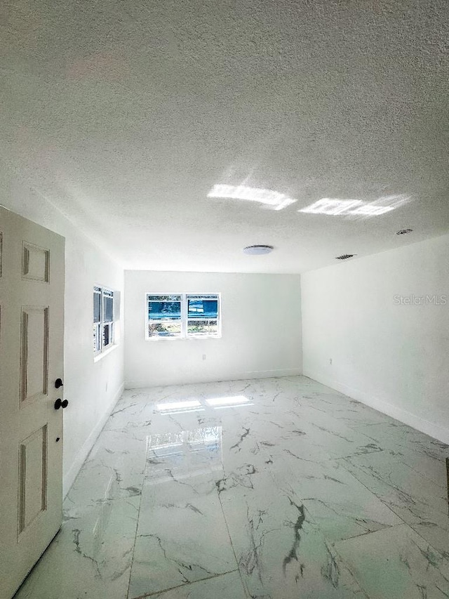 547 16th Ave S, Saint Petersburg, FL 33701 - unfurnished room featuring light marble finish flooring, baseboards, and a textured ceiling