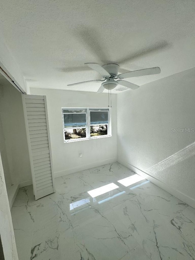 547 16th Ave S, Saint Petersburg, FL 33701 - unfurnished bedroom featuring baseboards, marble finish floors, a textured ceiling, a closet, and a ceiling fan