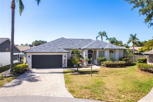 view of front facade with decorative driveway, a garage, a front lawn, and stucco siding