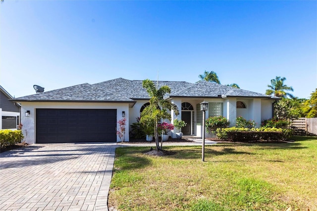 ranch-style home with an attached garage, decorative driveway, stucco siding, and a front yard
