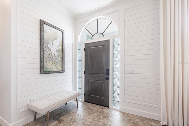 foyer entrance featuring stone finish flooring and wooden walls