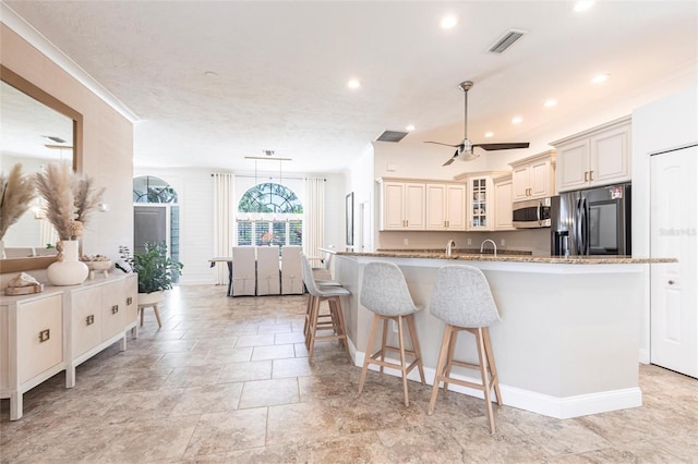 kitchen with visible vents, a breakfast bar area, stainless steel microwave, cream cabinets, and fridge with ice dispenser