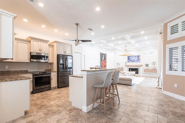kitchen with recessed lighting, appliances with stainless steel finishes, a breakfast bar area, and cream cabinetry